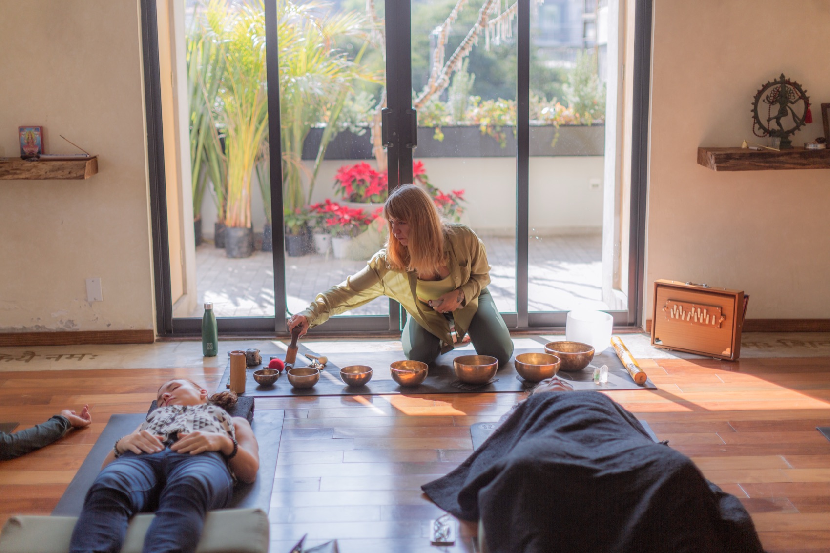A group sound bath in progress in a Mexico City studio, participants lying on mats in afternoon light