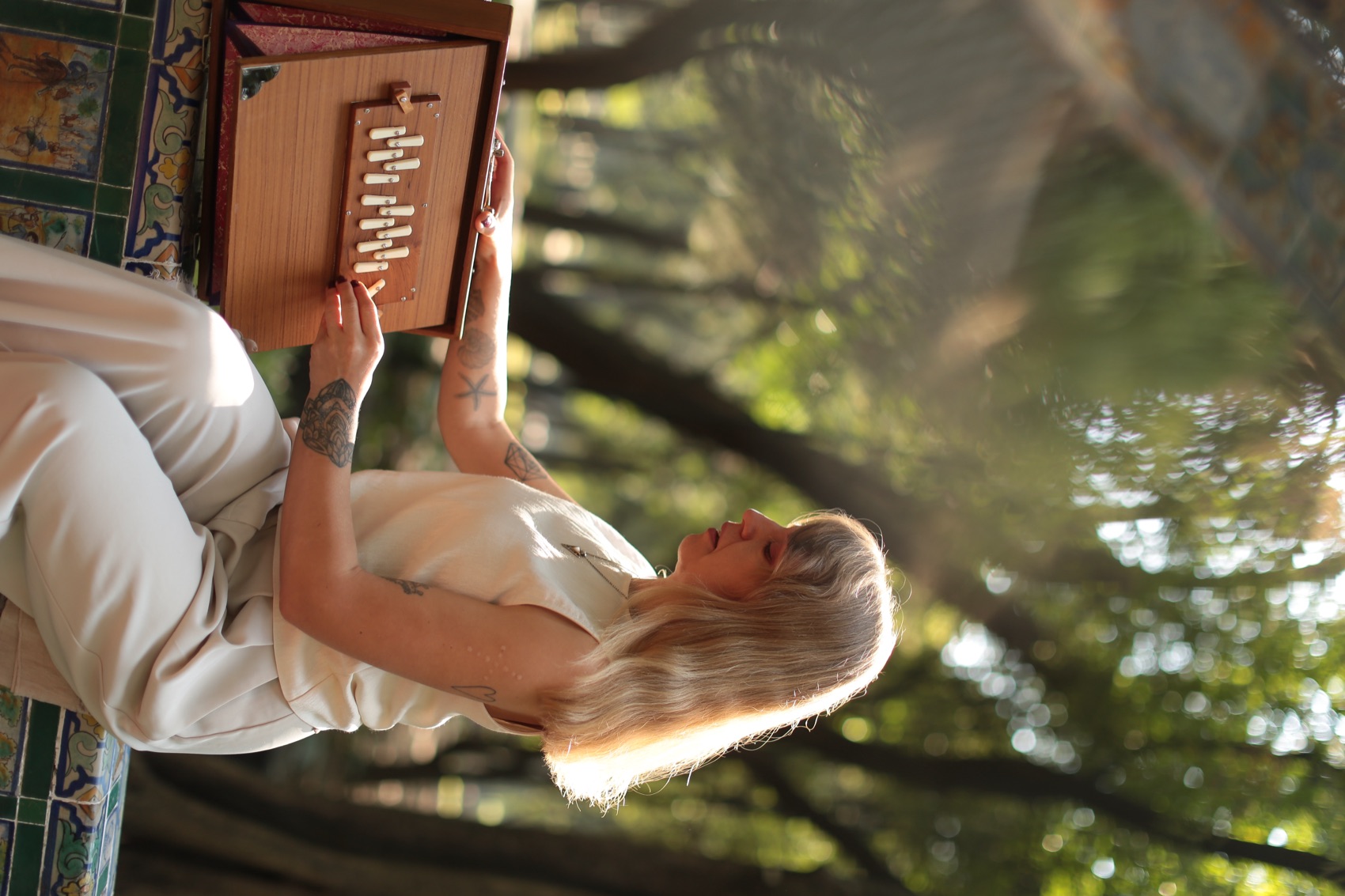 Julia Klykova playing a harmonium beside a tiled bench in a Mexico City park