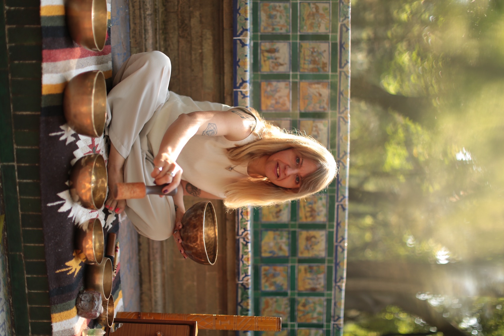 Julia Klykova seated with a Tibetan singing bowl among trees in a Mexico City park